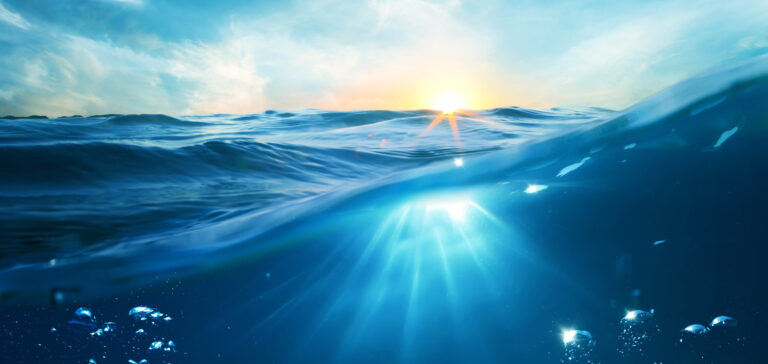 Solstrålar som skiner igenom havet.