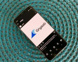Telefon som visar Gryaabs instagramkonto på en blå bakgrund.